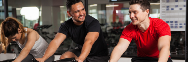 Two men on stationary bikes smiling