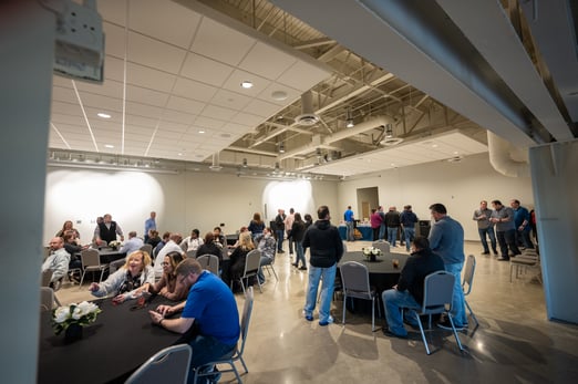 Event guests sit at round tables and stand around the room talking to one another