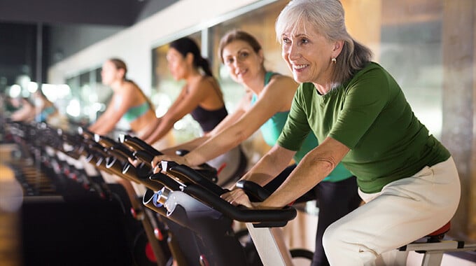 seniors riding on exercise bike inside gym