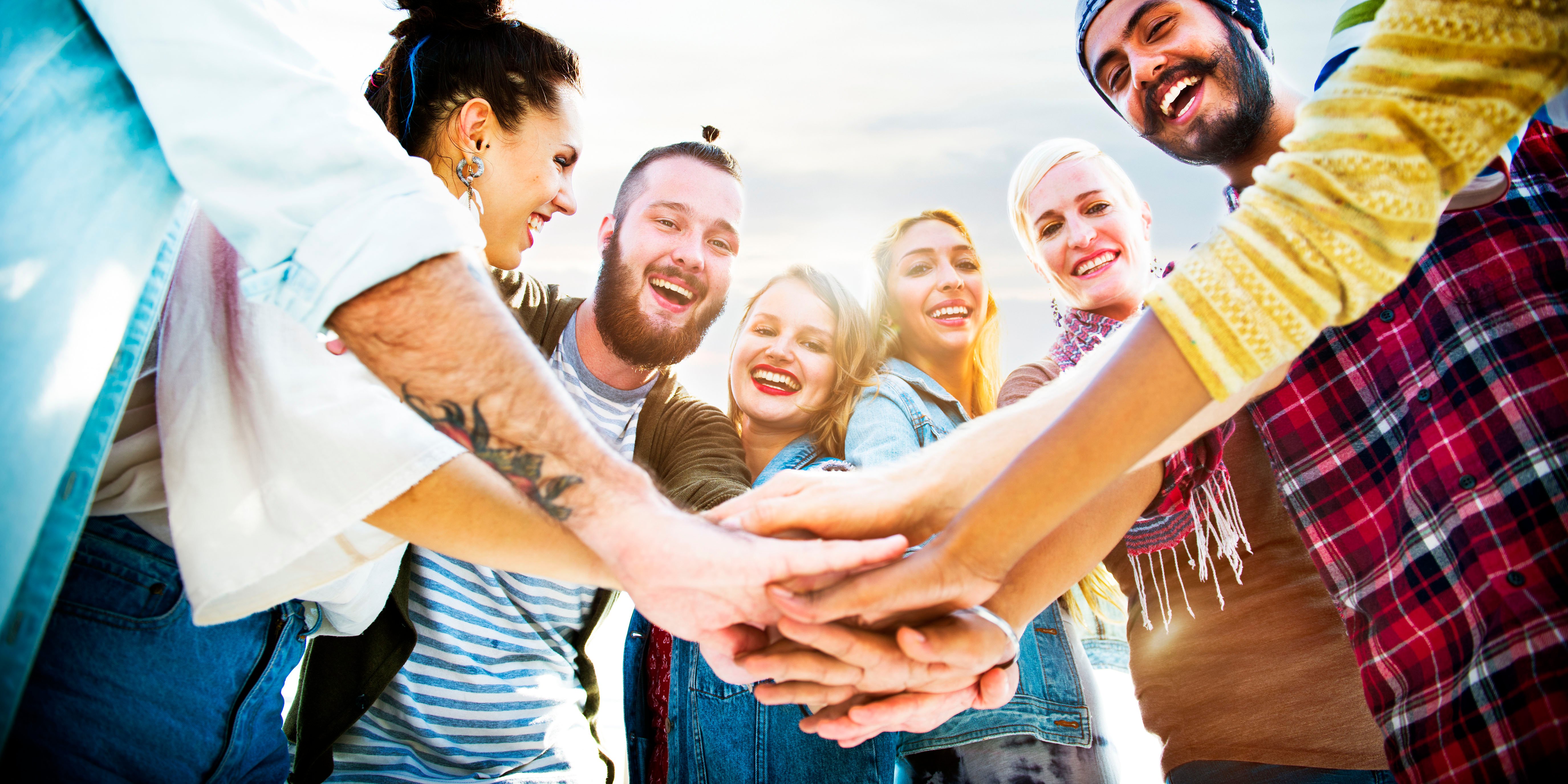 smiling people with hands piled together