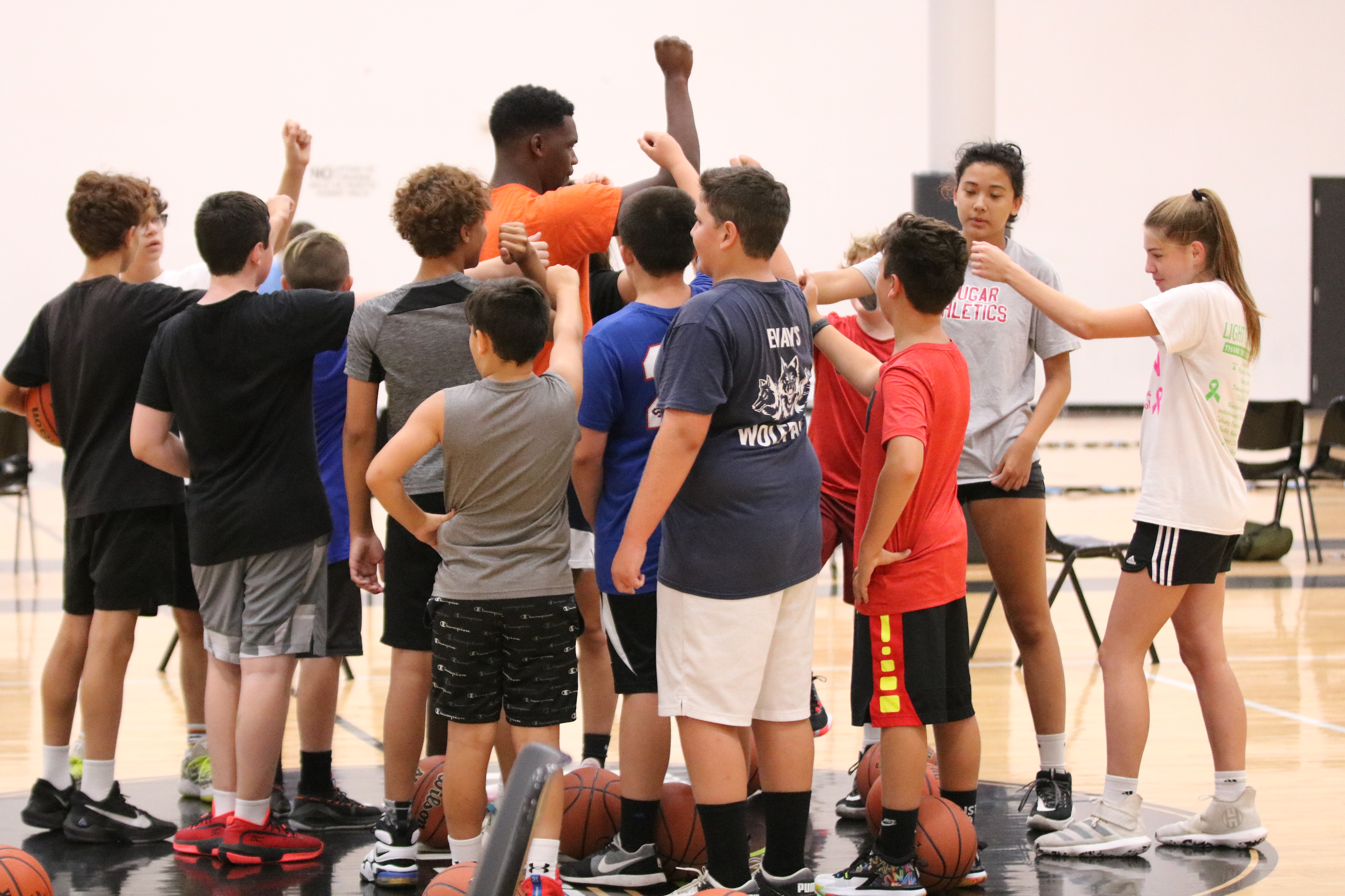 Children standing in a circle with their hands together in the center to cheer each other on at a summer camp in Hamilton, Ohio