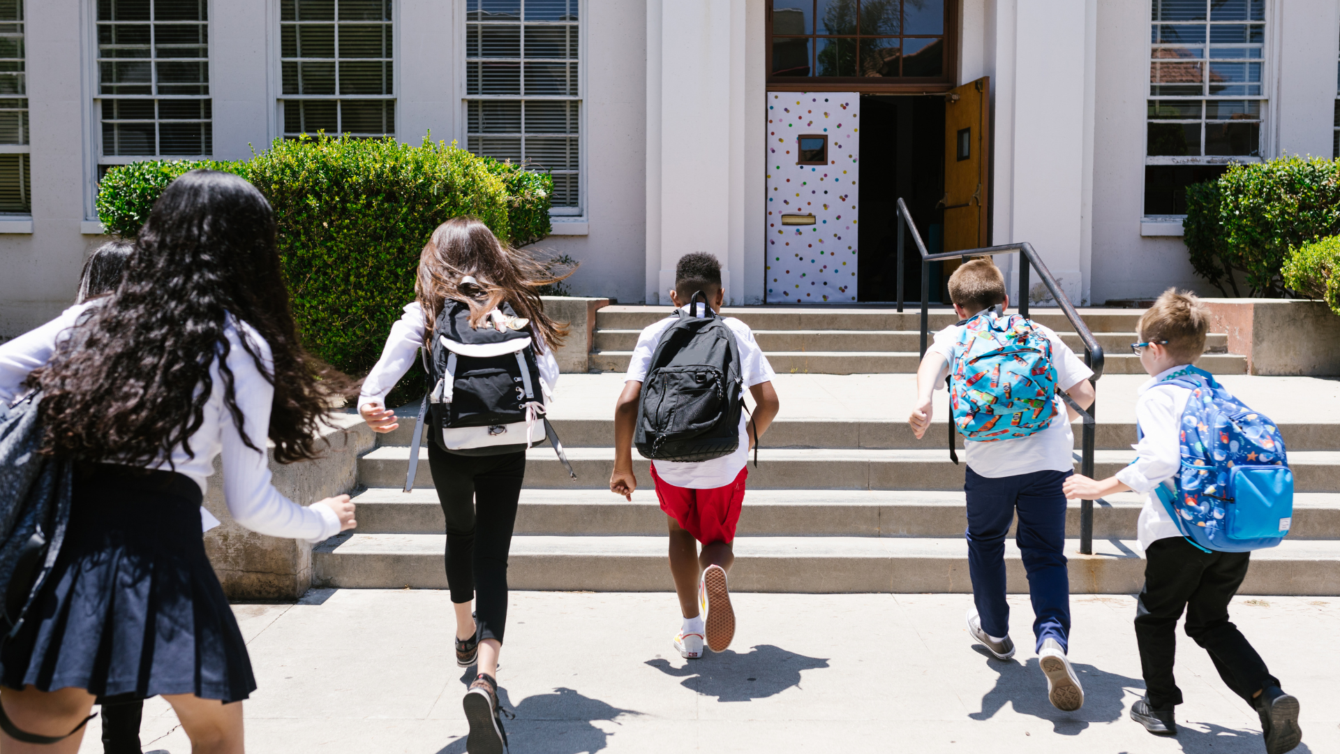 kids with backpacks running into school