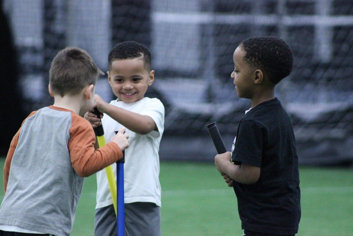 Smiling children holding field hockey sticks at a youth sports summer camps in Hamilton, Ohio