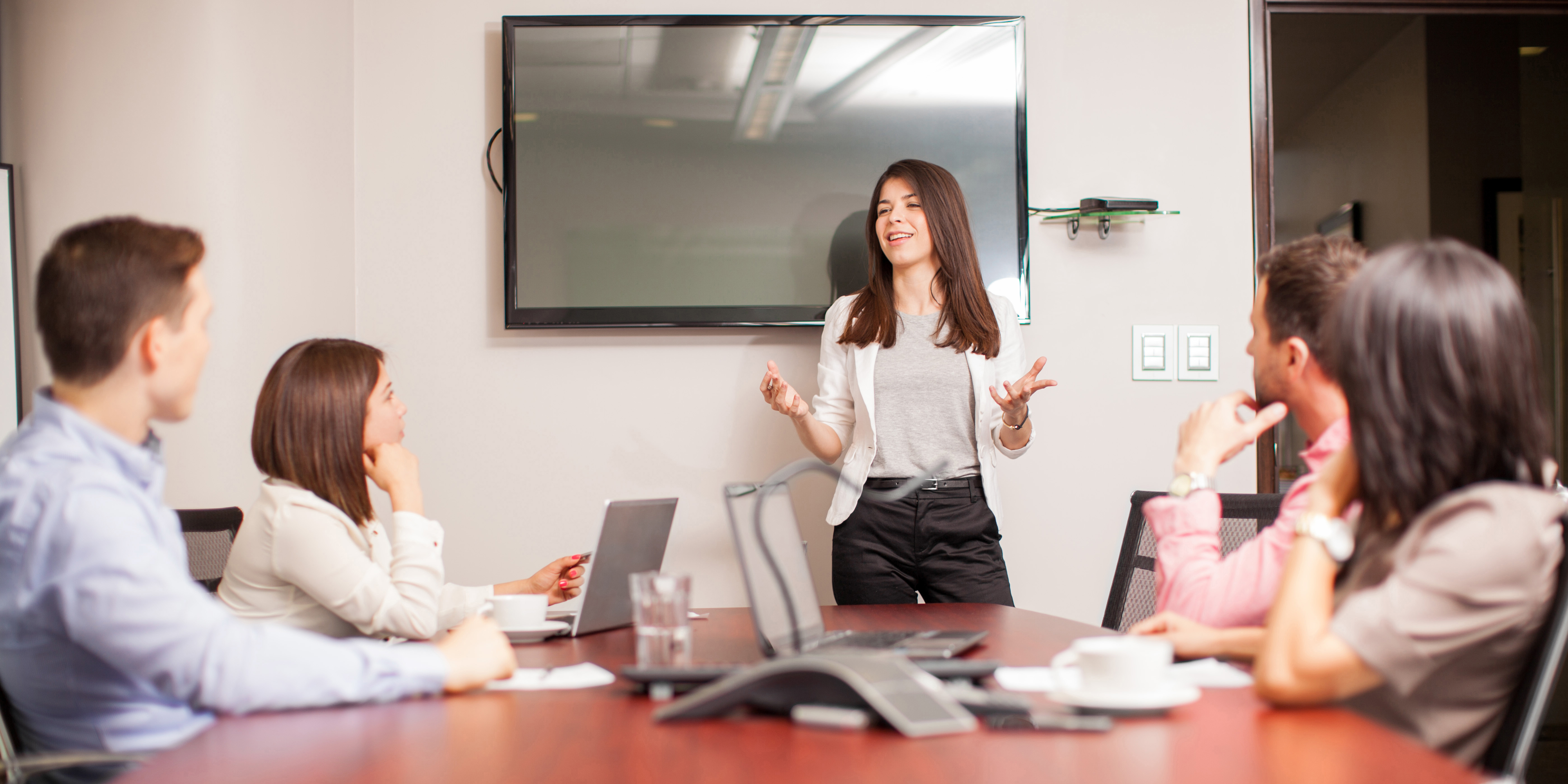 woman presenting to coworkers in conference room